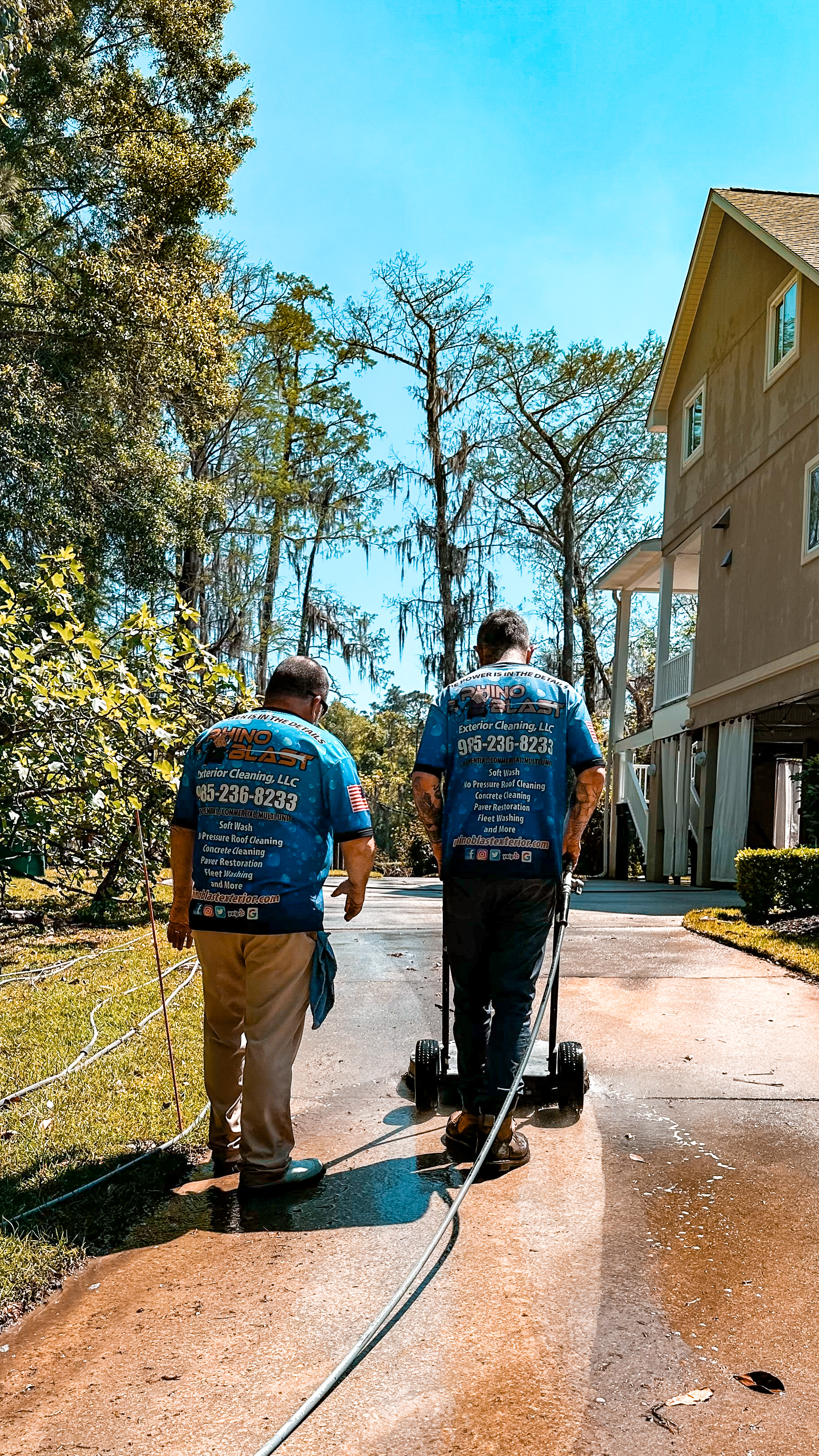 Two men pressure washing a driveway